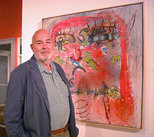 Portrait of Layne Meacham beside one of his paintings at a gallery opening